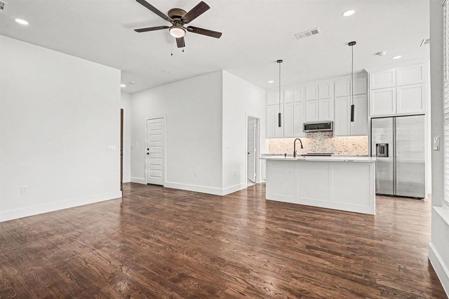 There are ceiling fans in living area and bedrooms for energy efficiency.  The kitchen has two upscale pendant lights and a custom tile backsplash.  Refrigerator included!