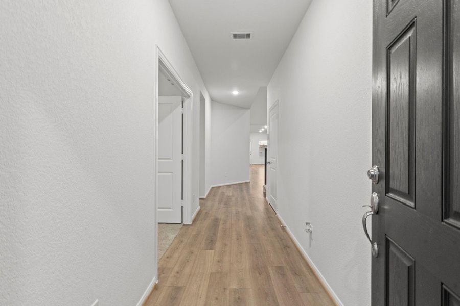 Step inside to a bright and airy hallway accented by stunning wood-like tile flooring and a clean modern design. Beautiful tile floors will lead you into the main living areas, offering a smooth transition into the open-concept floor plan.  To the left French doors open to your Home Office!