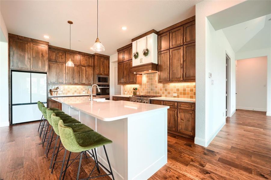 Dual tone kitchen featuring stainless steel appliances, dark wood finished floors, a breakfast bar, tasteful backsplash, and dual tone cabinetry