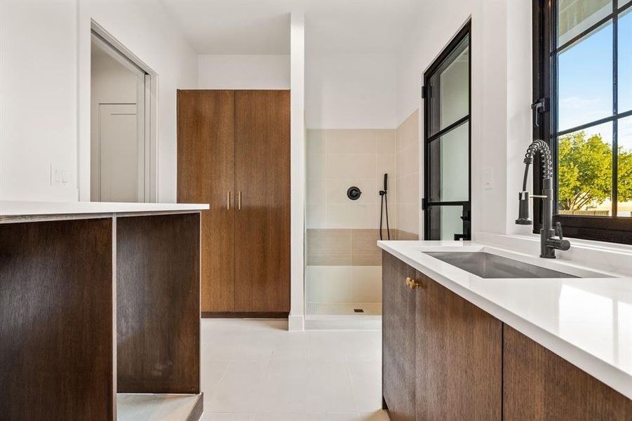 Bathroom with vanity, tiled shower, and light tile patterned floors Bathroom with vanity, tiled shower, and light tile patterned floors