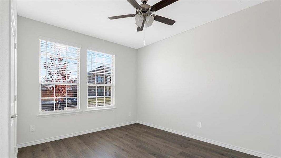 Room featuring two large windows with blinds, wood-finish flooring, a ceiling fan, and light-toned walls