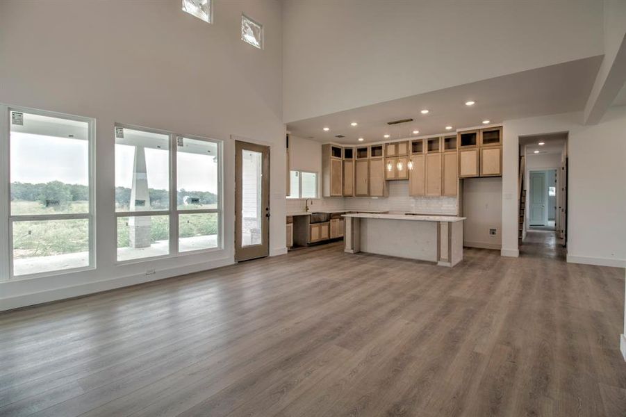 Kitchen featuring open floor plan, backsplash, dark wood-style flooring, light countertops, and a center island Kitchen featuring open floor plan, backsplash, dark wood-style flooring, light countertops, and a center island