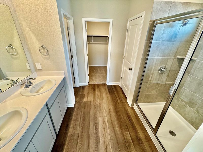 Full bath with a stall shower, wood finished floors, double vanity, and a walk in closet Full bath with a stall shower, wood finished floors, double vanity, and a walk in closet