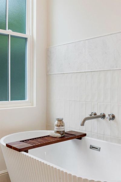 A deep soaking tub with elegant wall-mounted fixtures invites relaxation in this tranquil bathroom.
