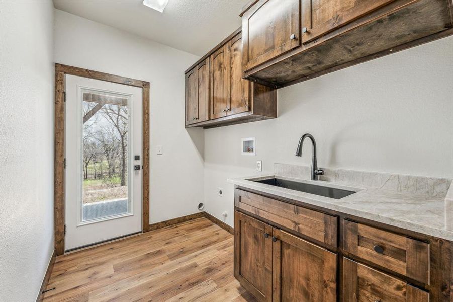Kitchen with plenty of natural light, baseboards, light wood-style flooring, and a sink