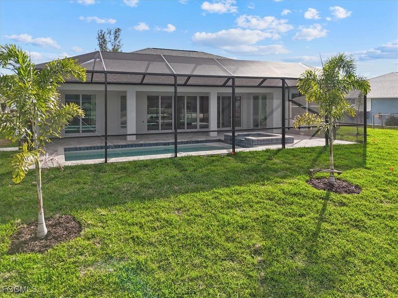 Rear view of property with screen enclosure, a sunroom, stucco siding, and a lawn