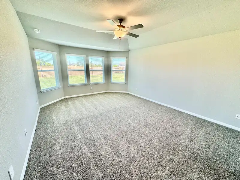 Carpeted empty room with a ceiling fan and a textured ceiling Carpeted empty room with a ceiling fan and a textured ceiling