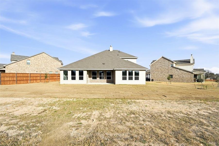 Back of property with a patio, roof with shingles, and a chimney