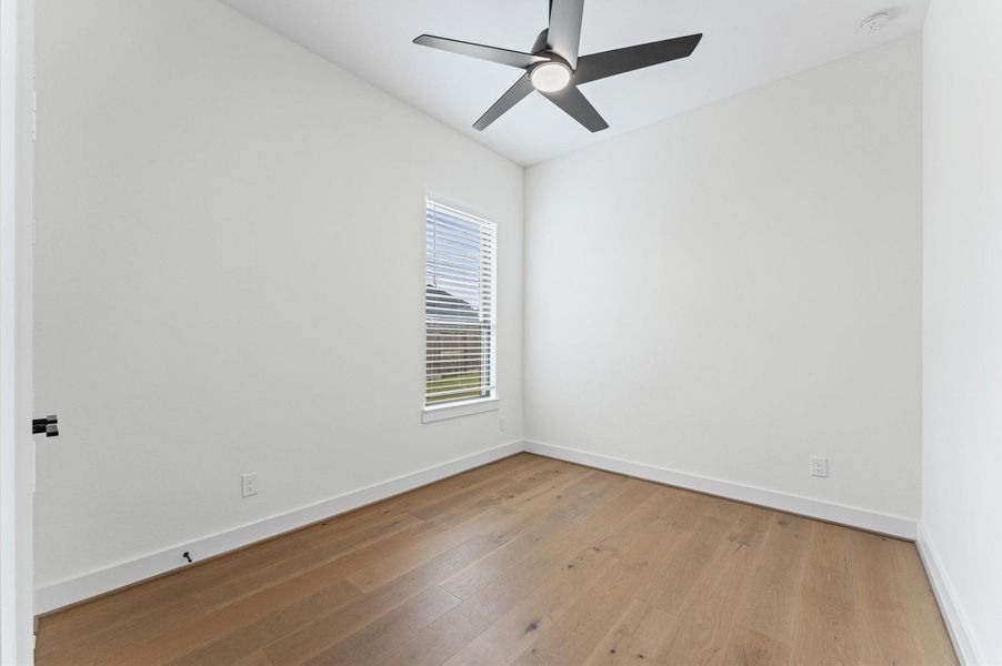 Spacious secondary bedroom with hardwood-look flooring, ceiling fan, and a clean neutral palette — ready for your vision.