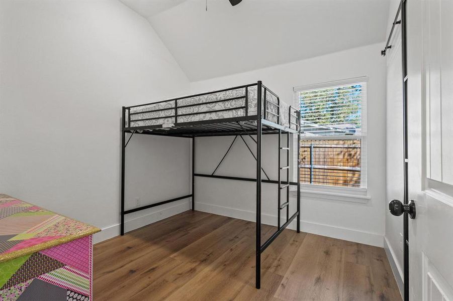 Unfurnished bedroom with light wood-style flooring, lofted ceiling, and a ceiling fan