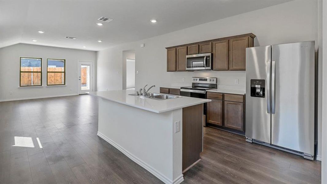 Kitchen featuring stainless steel appliances, recessed lighting, a center island with sink, dark wood-type flooring, and open floor plan Kitchen featuring stainless steel appliances, recessed lighting, a center island with sink, dark wood-type flooring, and open floor plan
