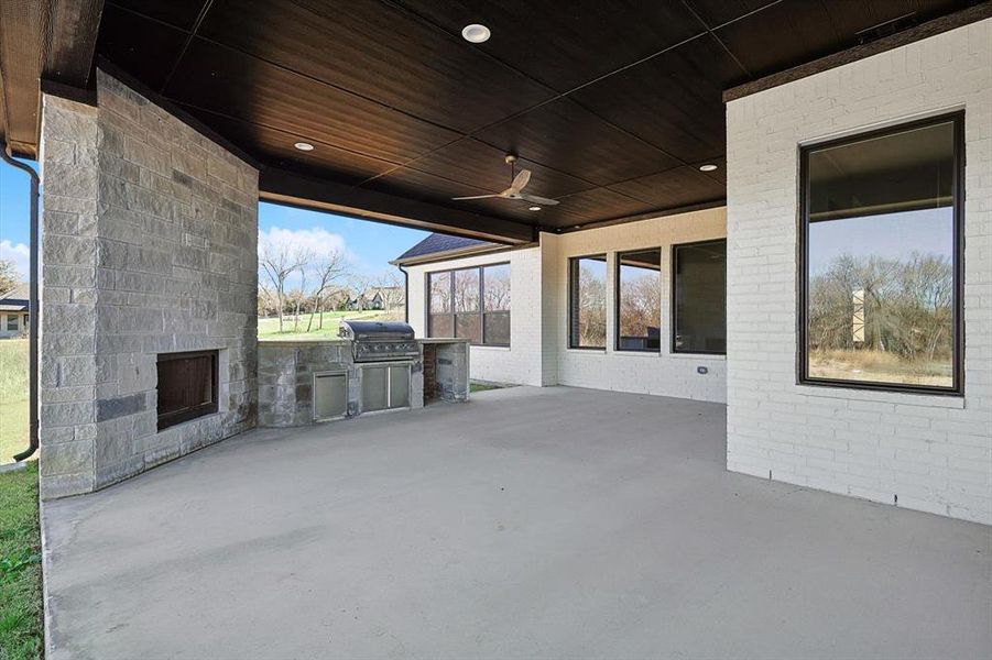 View of patio / terrace featuring area for grilling, a grill, ceiling fan, and an outdoor stone fireplace