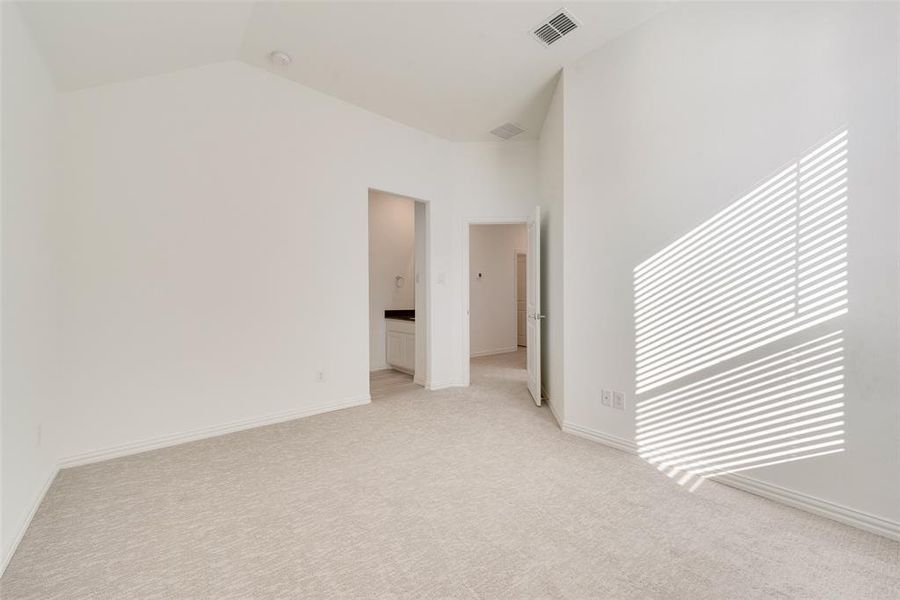 Carpeted empty room featuring high vaulted ceiling