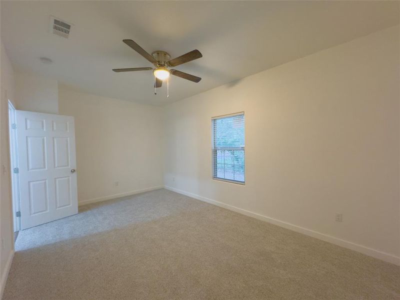 Carpeted empty room featuring ceiling fan, window covering