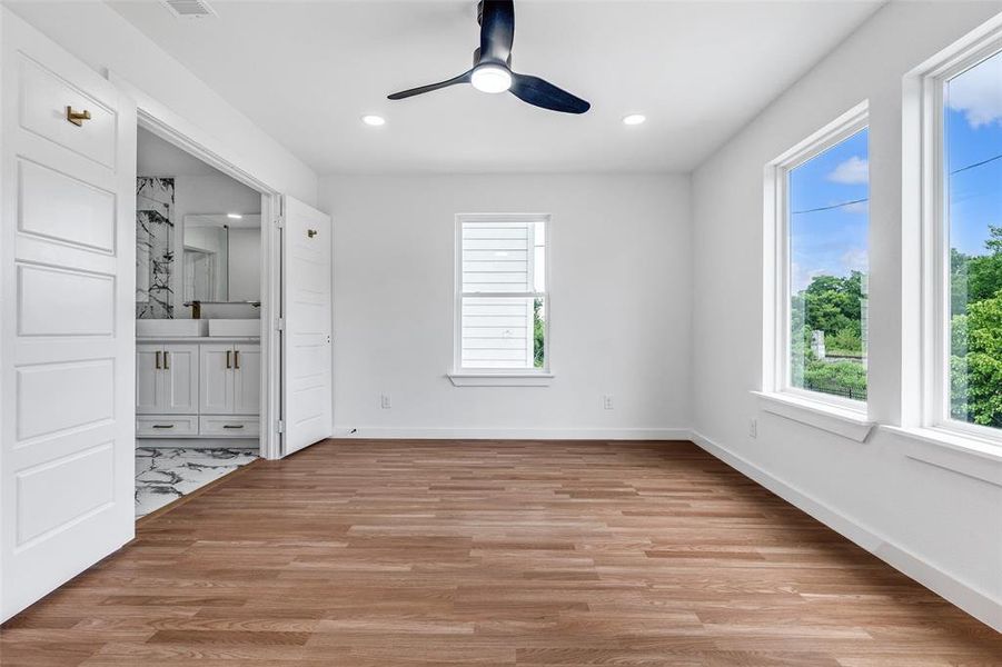 Unfurnished bedroom featuring light wood-style flooring, a ceiling fan, recessed lighting, and connected bathroom Unfurnished bedroom featuring light wood-style flooring, a ceiling fan, recessed lighting, and connected bathroom