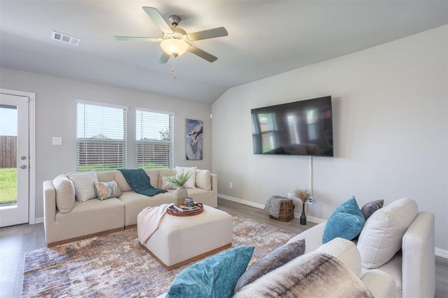 Living area featuring wood finished floors, a ceiling fan, and vaulted ceiling Living area featuring wood finished floors, a ceiling fan, and vaulted ceiling