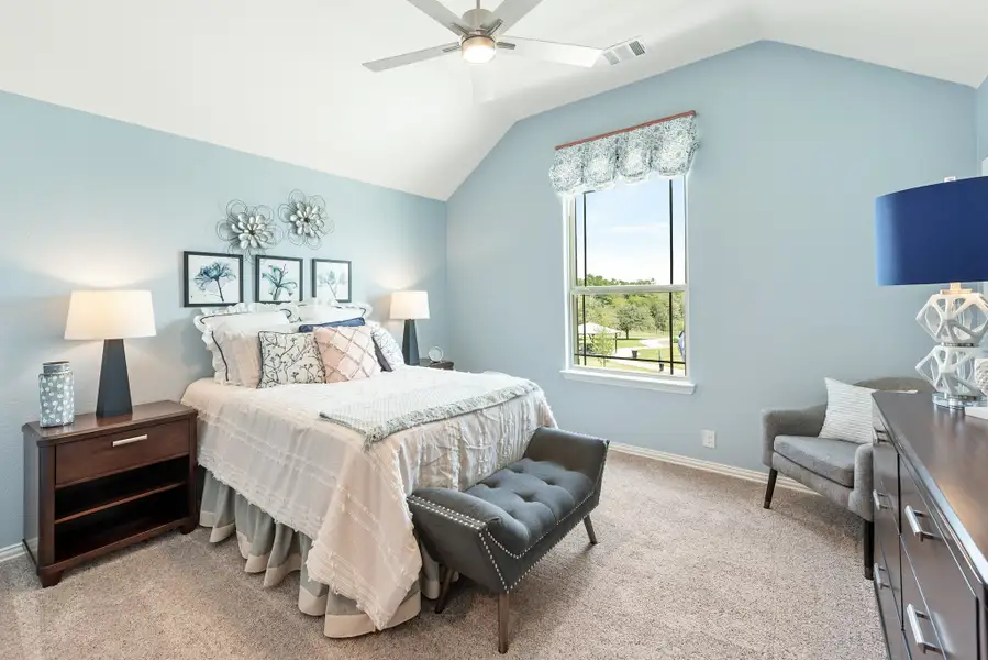 Bedroom with vaulted ceiling, ceiling fan, blue walls, and carpet flooring
