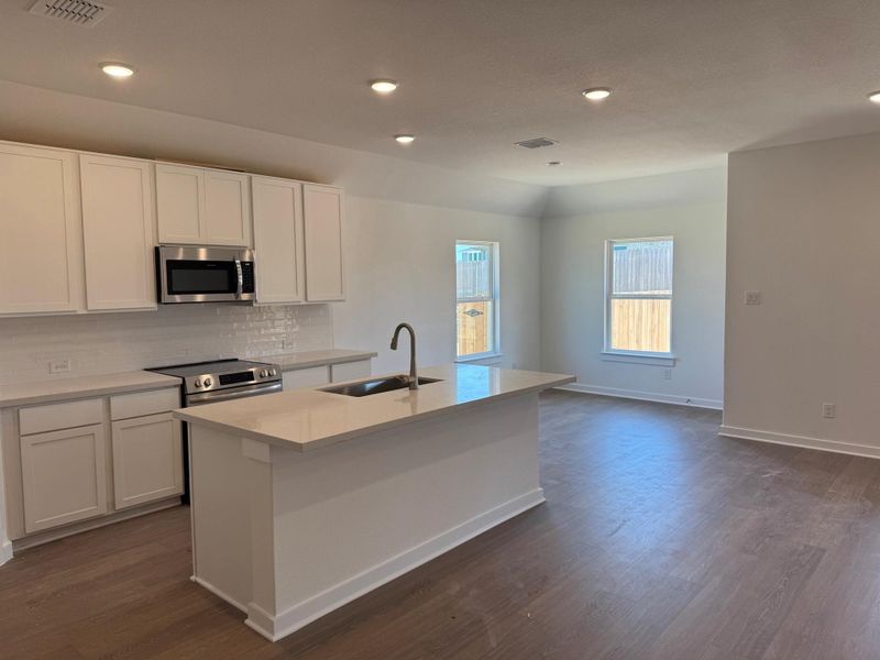 Kitchen featuring appliances with stainless steel finishes, dark wood-type flooring, a kitchen island with sink, decorative backsplash, and white cabinets Kitchen featuring appliances with stainless steel finishes, dark wood-type flooring, a kitchen island with sink, decorative backsplash, and white cabinets