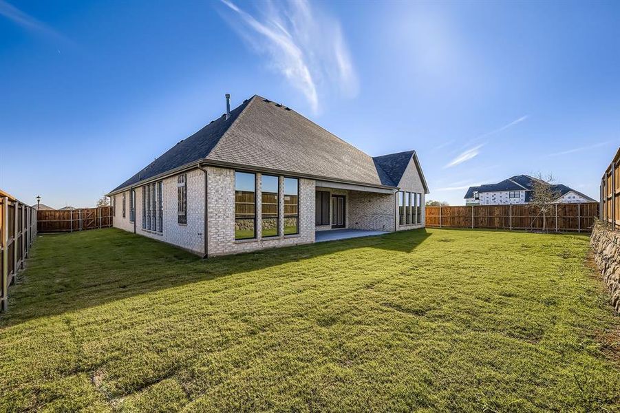 Rear view of house with roof with shingles, a patio area, brick siding, and a fenced backyard