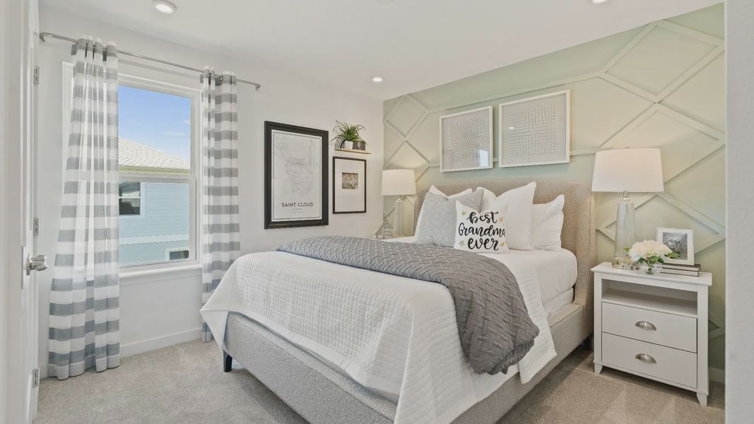Carpeted secondary bedroom with large window in a DRB Homes Ambersweet model at the Trinity Place community. Carpeted secondary bedroom with large window in a DRB Homes Ambersweet model at the Trinity Place community.