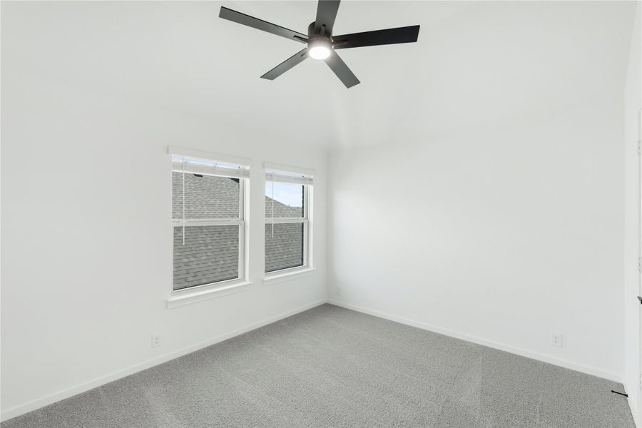 Empty bedroom with gray carpet, ceiling fan, and two windows with white trim Empty bedroom with gray carpet, ceiling fan, and two windows with white trim