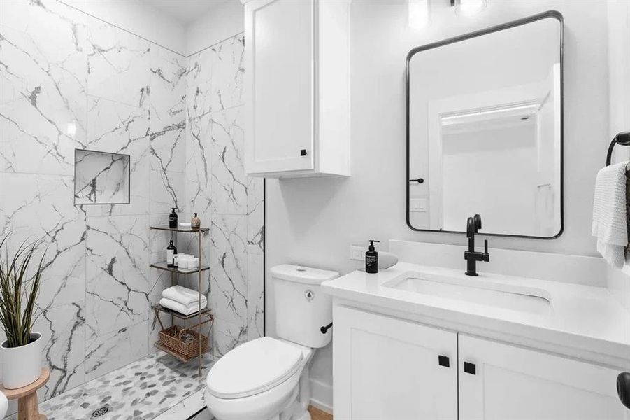 Bathroom featuring vanity and a marble finish shower