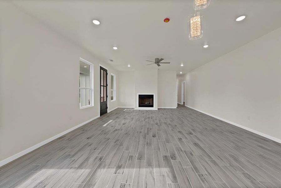 Unfurnished living room featuring light wood-style floors, recessed lighting, a fireplace, and a ceiling fan