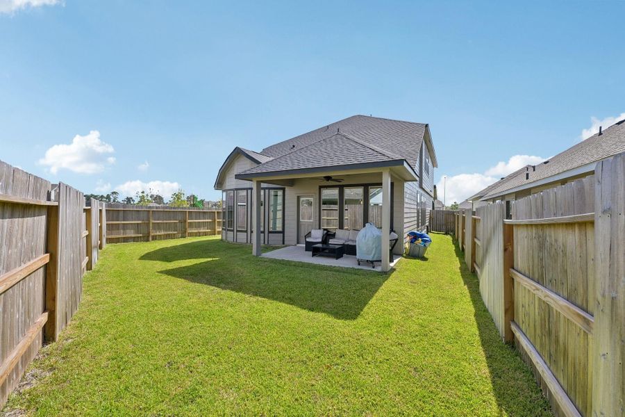 Spacious backyard with a covered patio, perfect for outdoor relaxation and entertainment, surrounded by a privacy fence.