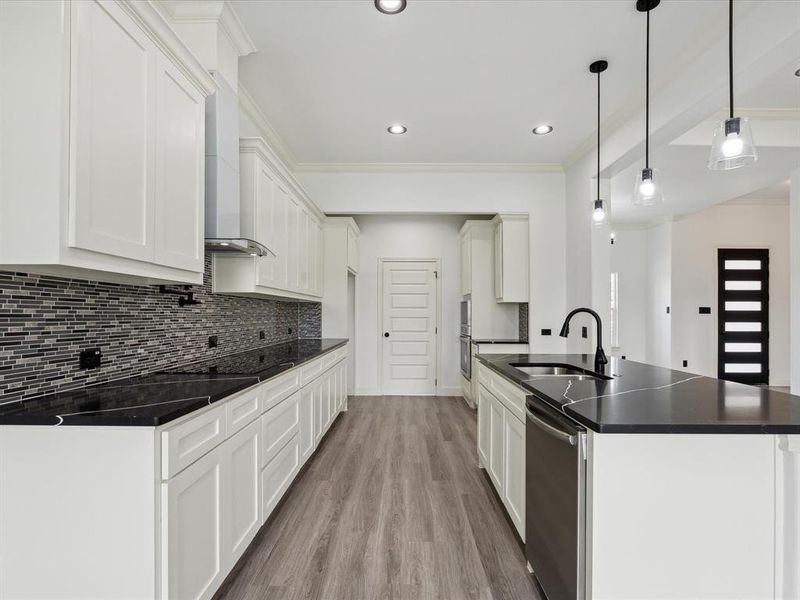 Kitchen with white cabinets, pendant lighting, stainless steel dishwasher, light wood-type flooring, and sink