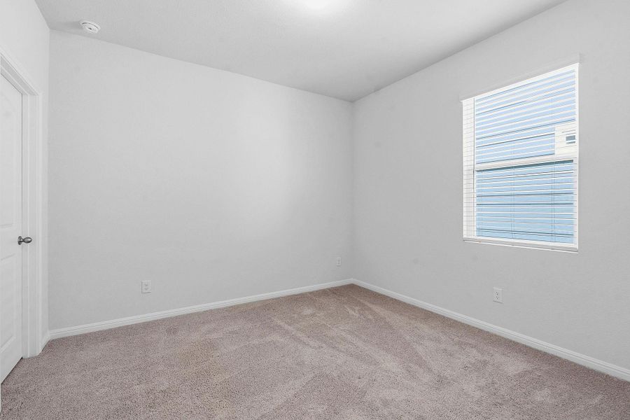 A spacious, naturally illuminated room featuring plush carpeting and a wide window with blinds. A spacious, naturally illuminated room featuring plush carpeting and a wide window with blinds.