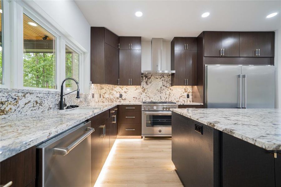 Contemporary kitchen featuring dark wood cabinetry, light-toned stone countertops, and a matching stone backsplash