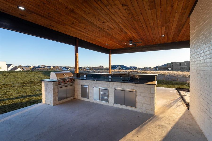 View of patio with ceiling fan, an outdoor kitchen, sink, and grilling area