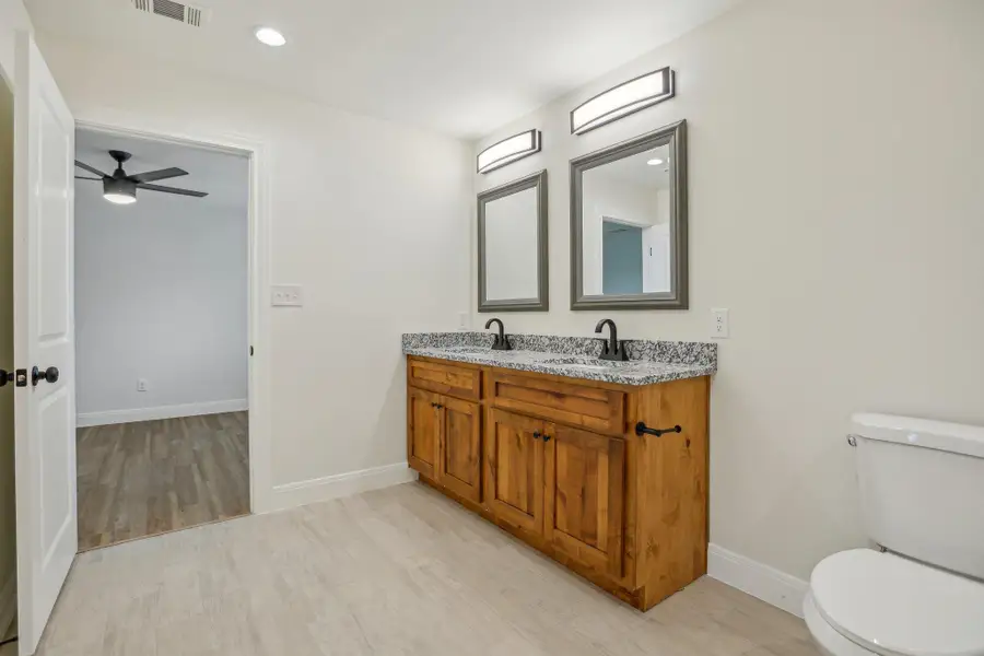 Jack and Jill Bathroom with wood tile floors, visible vents, toilet, and a sink