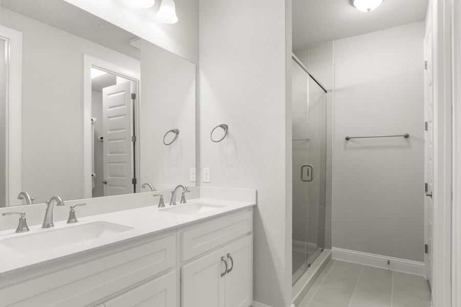 Image of primary with white cabinets and a jack and jill vanity with a large mirror and a walk-in shower