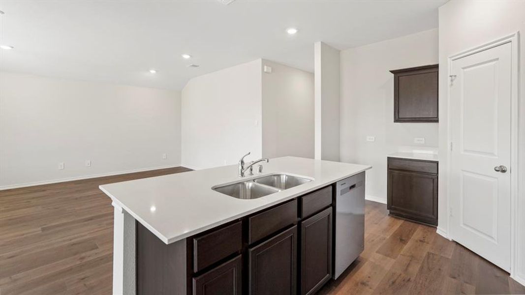Kitchen island featuring a dual-basin stainless steel sink, a stainless steel dishwasher, and a white countertop