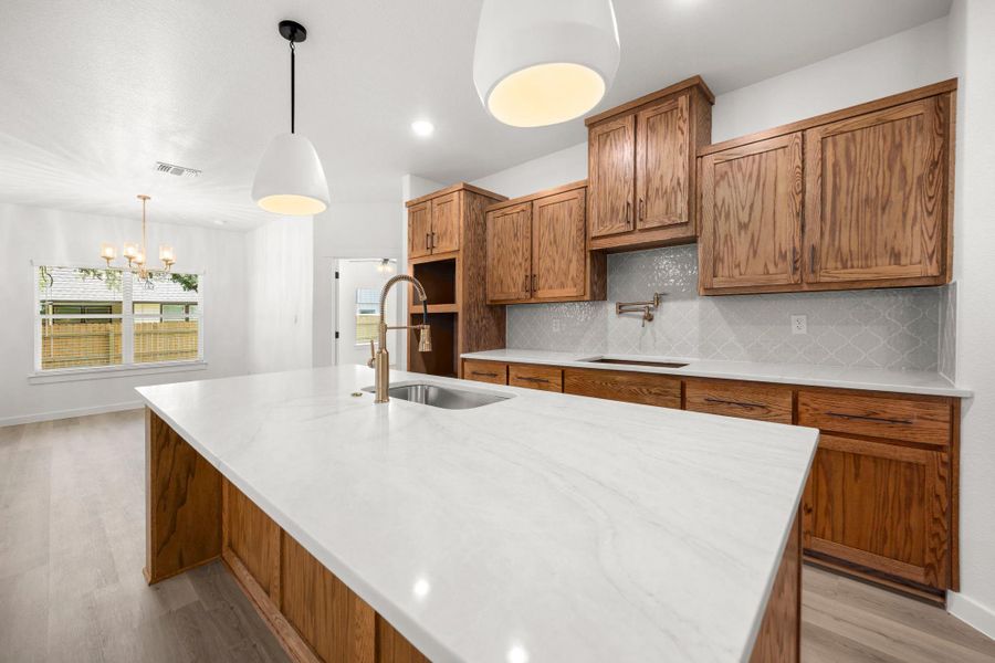 A well-appointed kitchen features a waterfall-edge island, rich cabinetry, and chic pendant lighting. A well-appointed kitchen features a waterfall-edge island, rich cabinetry, and chic pendant lighting.
