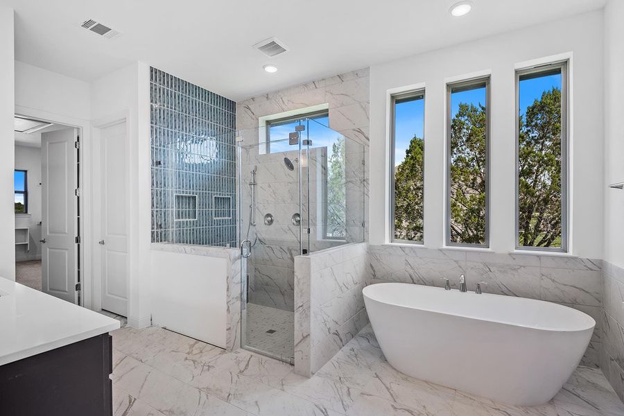 Full bathroom with light marble finish floors, a soaking tub, tile walls, a marble finish shower, and vanity