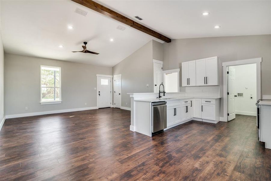 Kitchen featuring ceiling fan, sink, beamed ceiling, dishwasher, and white cabinetry