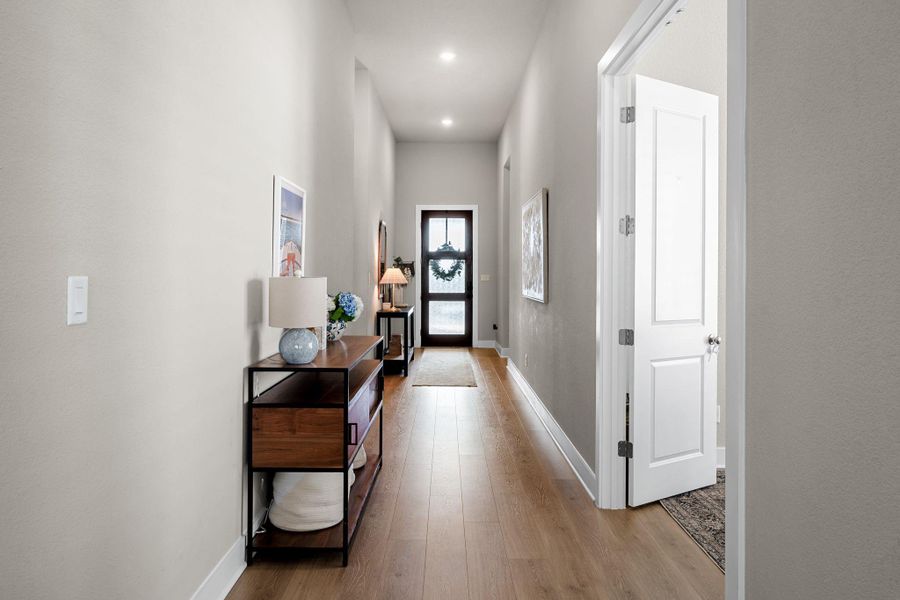 Inviting entryway featuring wood-finish flooring, recessed lighting, and a dark-paneled door with glass inserts