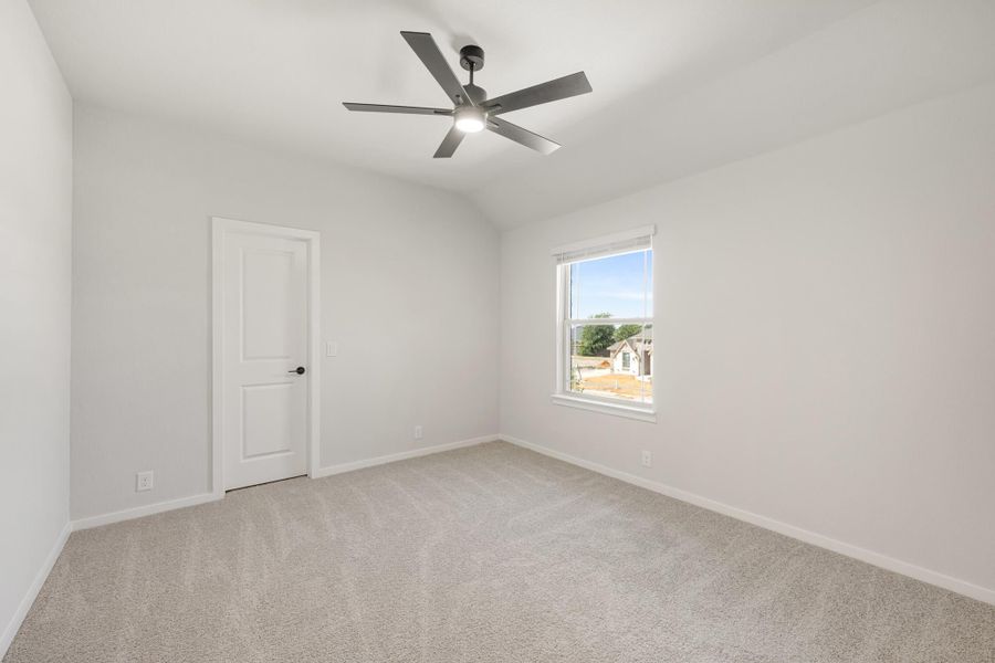Empty bedroom with carpet flooring, ceiling fan, vaulted ceiling, and single window with natural light Empty bedroom with carpet flooring, ceiling fan, vaulted ceiling, and single window with natural light