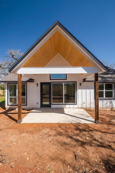 Back of house with board and batten siding and a patio area