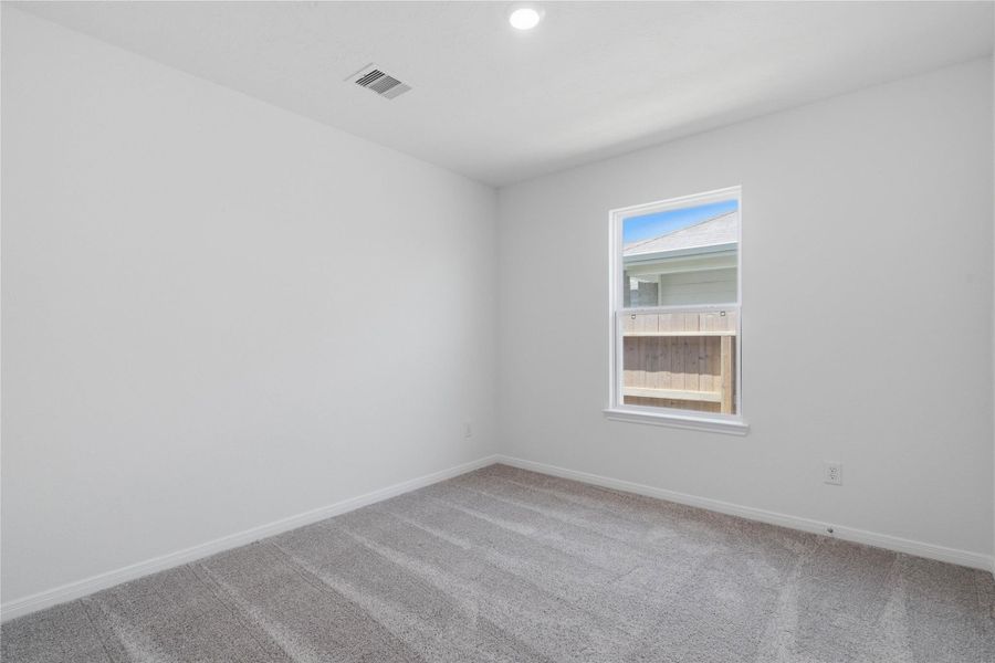 This secondary bedroom offers comfort and style with plush carpet flooring, neutral paint tones, a large window, and ample sized closet space.