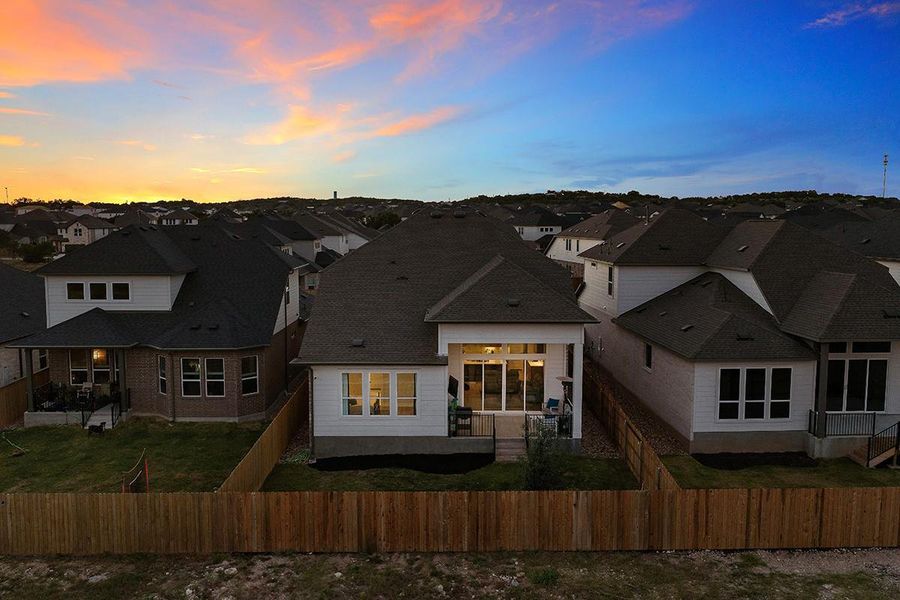 A fenced backyard anchors this classic single-family home under a twilight sky.