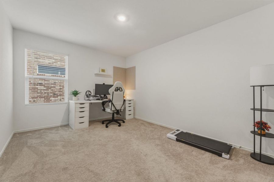 This room features neutral-toned carpeting, a window with blinds, and white walls, providing a versatile space