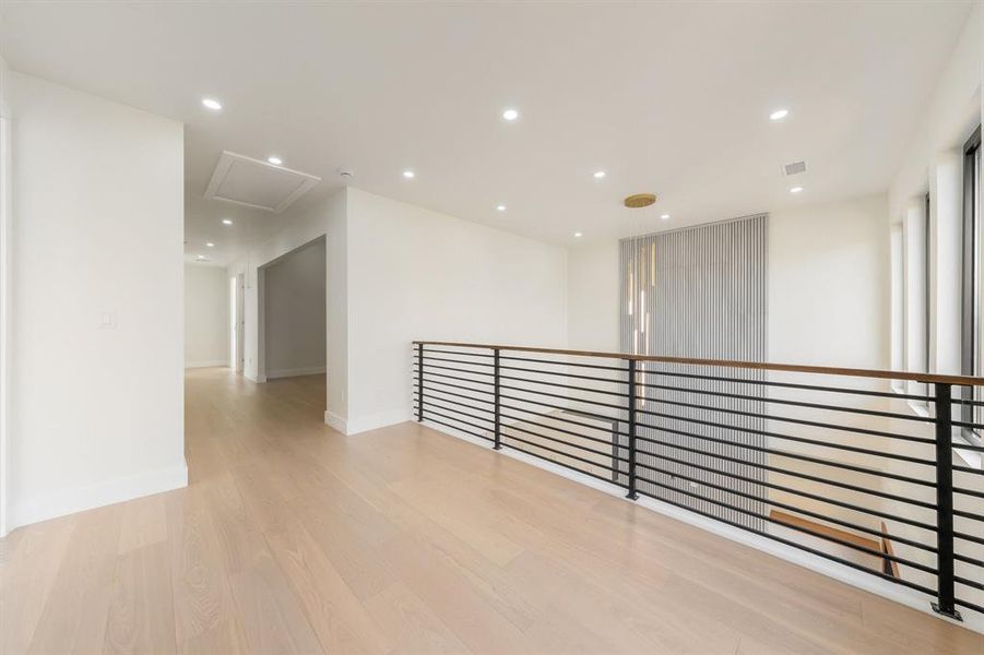Hallway with recessed lighting, light wood-style flooring, and an upstairs landing Hallway with recessed lighting, light wood-style flooring, and an upstairs landing