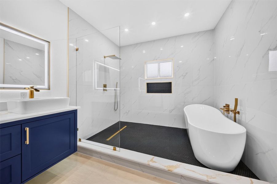 Spacious bathroom featuring a freestanding tub, large shower and bold contrasting vanity