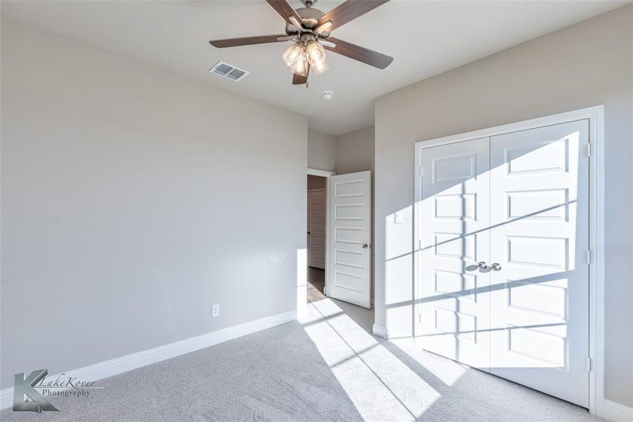 Unfurnished bedroom featuring light colored carpet and a ceiling fan