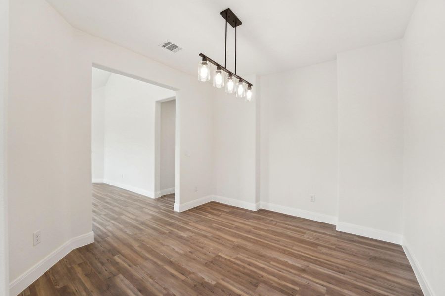 Formal Dining area or office, area with dark wood-style vinyl flooring, baseboards, and visible vents Formal Dining area or office, area with dark wood-style vinyl flooring, baseboards, and visible vents