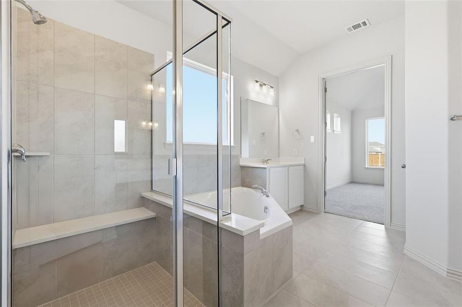 Full bath with a bath, a stall shower, vanity, light tile patterned floors, and vaulted ceiling Full bath with a bath, a stall shower, vanity, light tile patterned floors, and vaulted ceiling