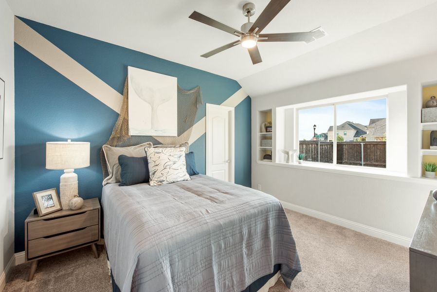 Bedroom with blue geometric accent wall, ceiling fan, built-in shelves, and large window